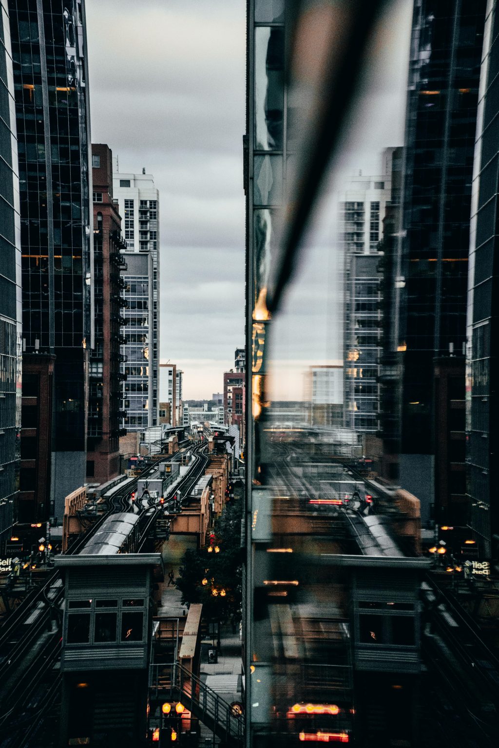 View of Chicago's elevated train with city reflections at twilight.